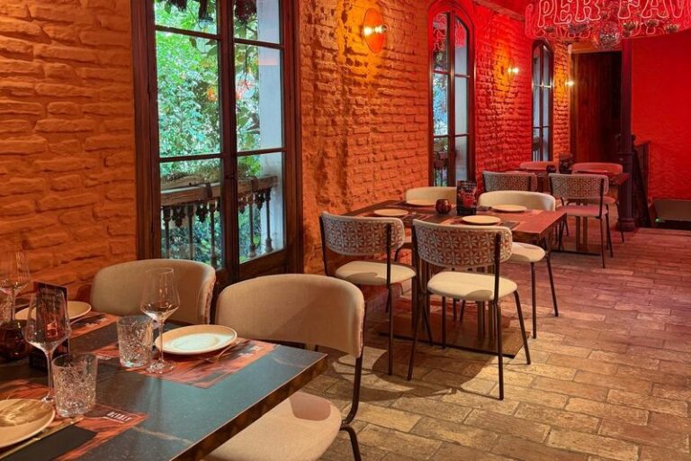 Comedor para disfrutar de la gastronomía italiana en Ditaly Jerez, con ventanales al jardín y el neón Per Favore