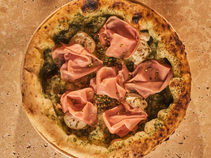 Fotografía de la pizza de Ditaly con salsa de pesto y mortadella di bologna que todo el mundo debería probar una vez en su vida.