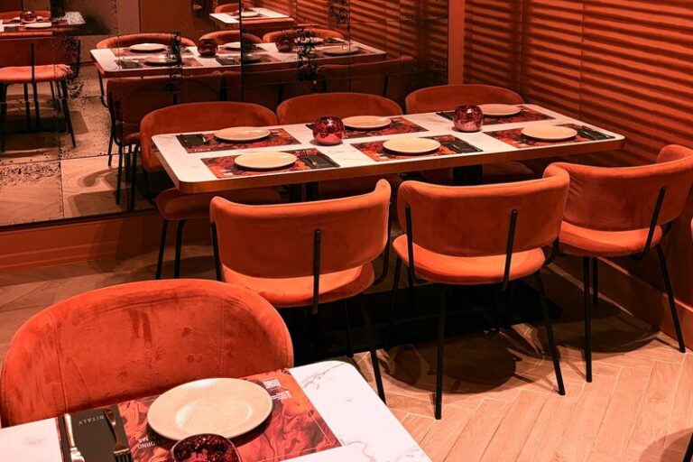Mesas con sillas de terciopelo y espejos envejecidos en Ditaly, un espacio acogedor para comer pizza italiana en el centro de Cádiz.